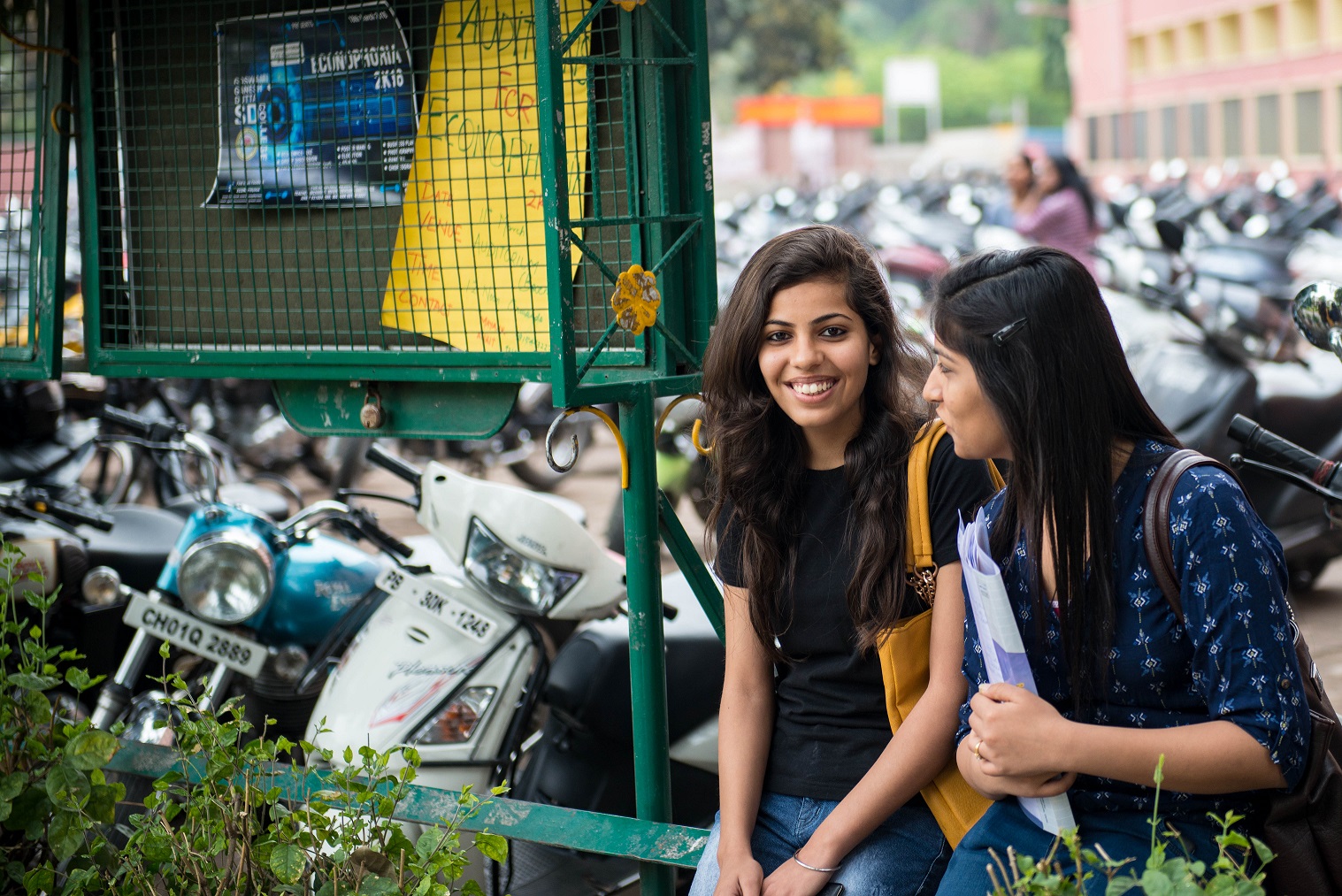 Photo of Two Girls with school bags near motorcycles