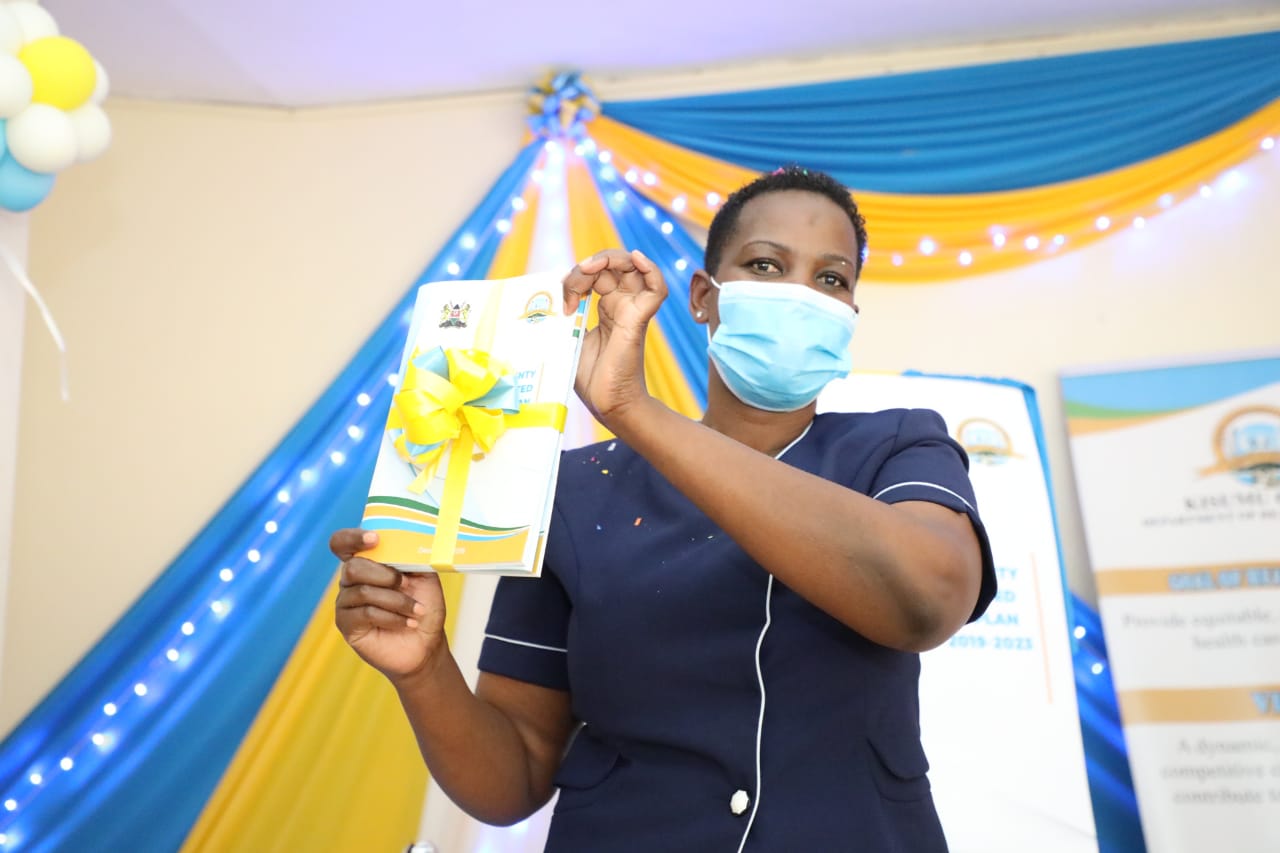 A woman holds a ceremonial copy of the costed implementation plan